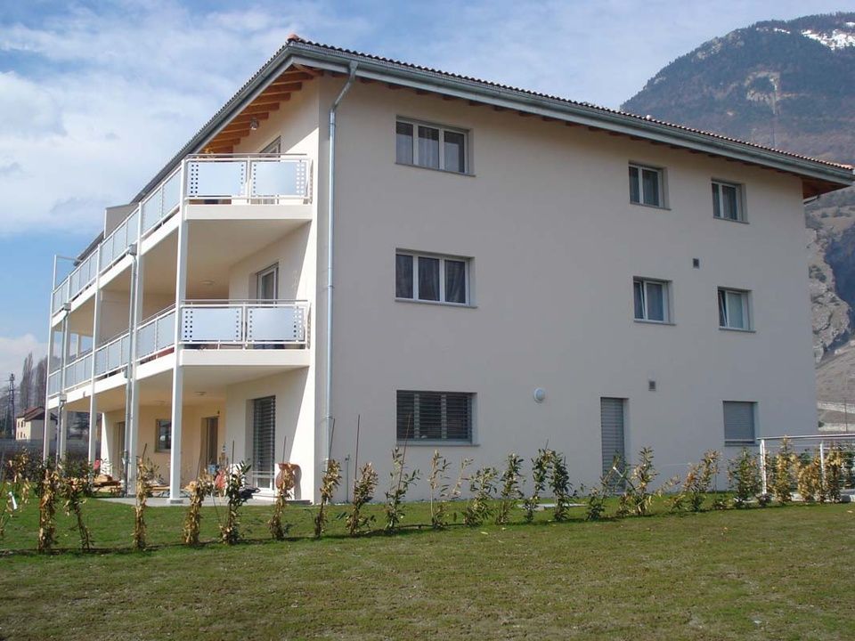 Un grand bâtiment blanc avec des balcons et des montagnes en arrière-plan