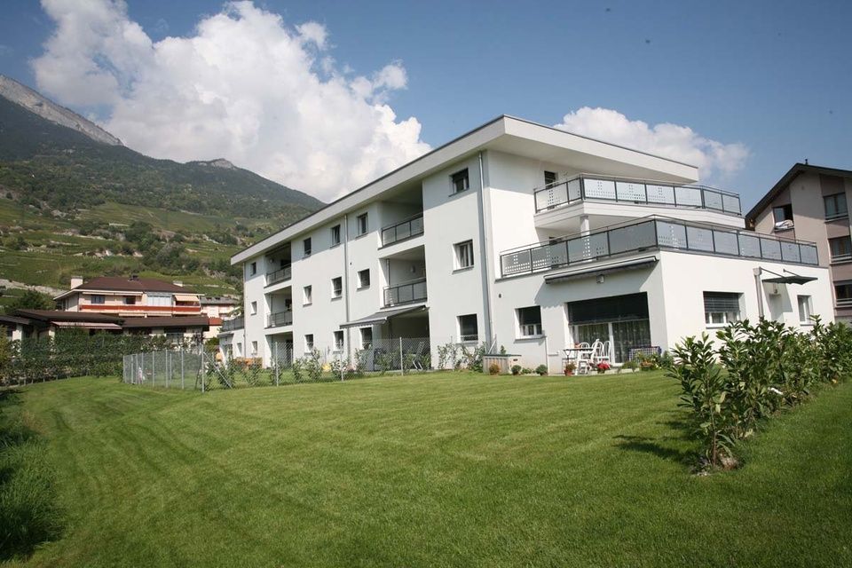 Un grand bâtiment blanc avec une pelouse verte luxuriante devant lui