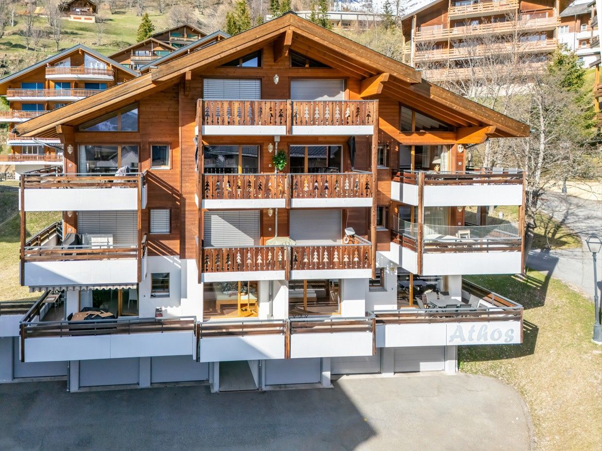 Chalet en bois avec balcons, niché à flanc de colline.