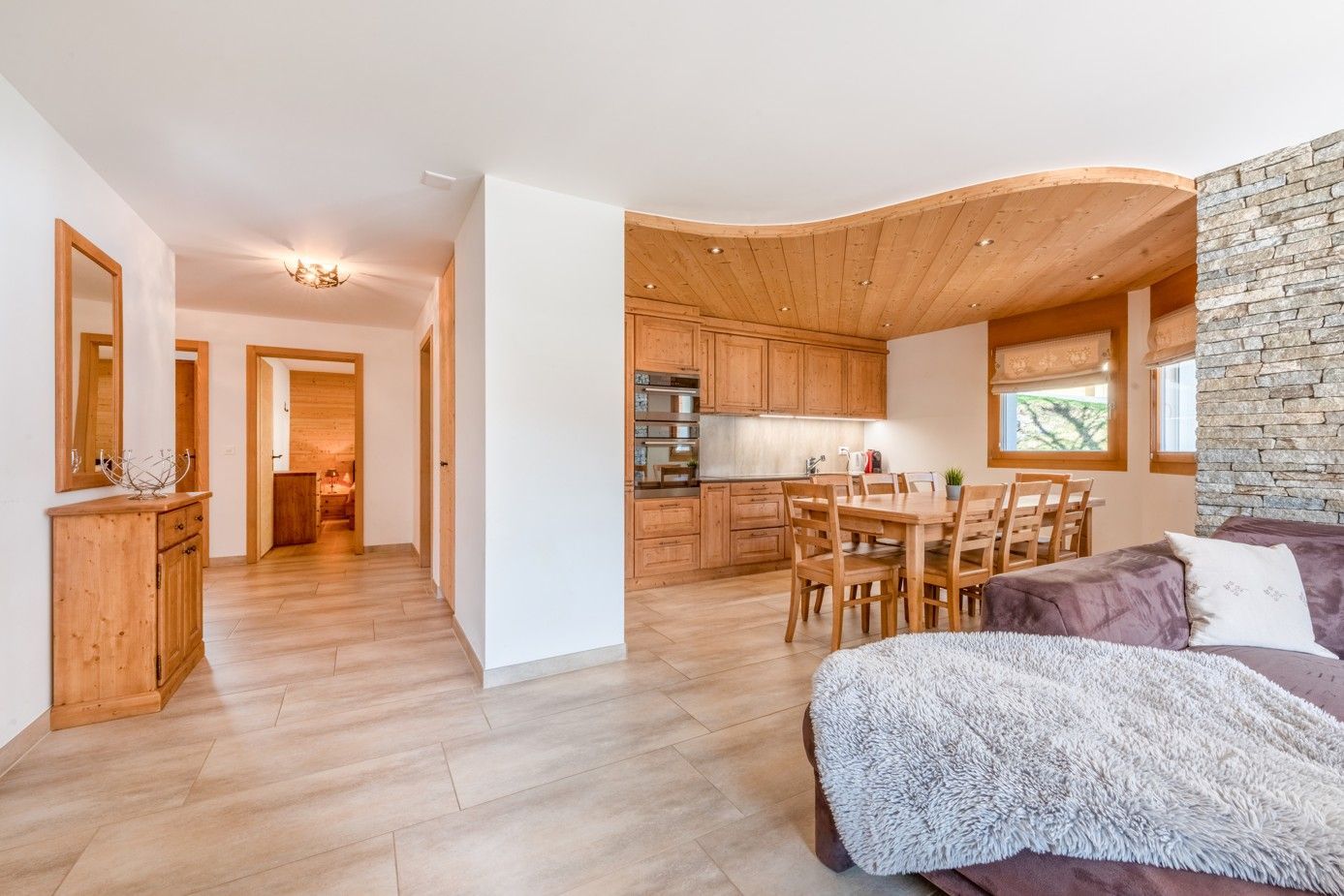 Appartement confortable et décloisonné avec des éléments en bois et un mur en pierre.