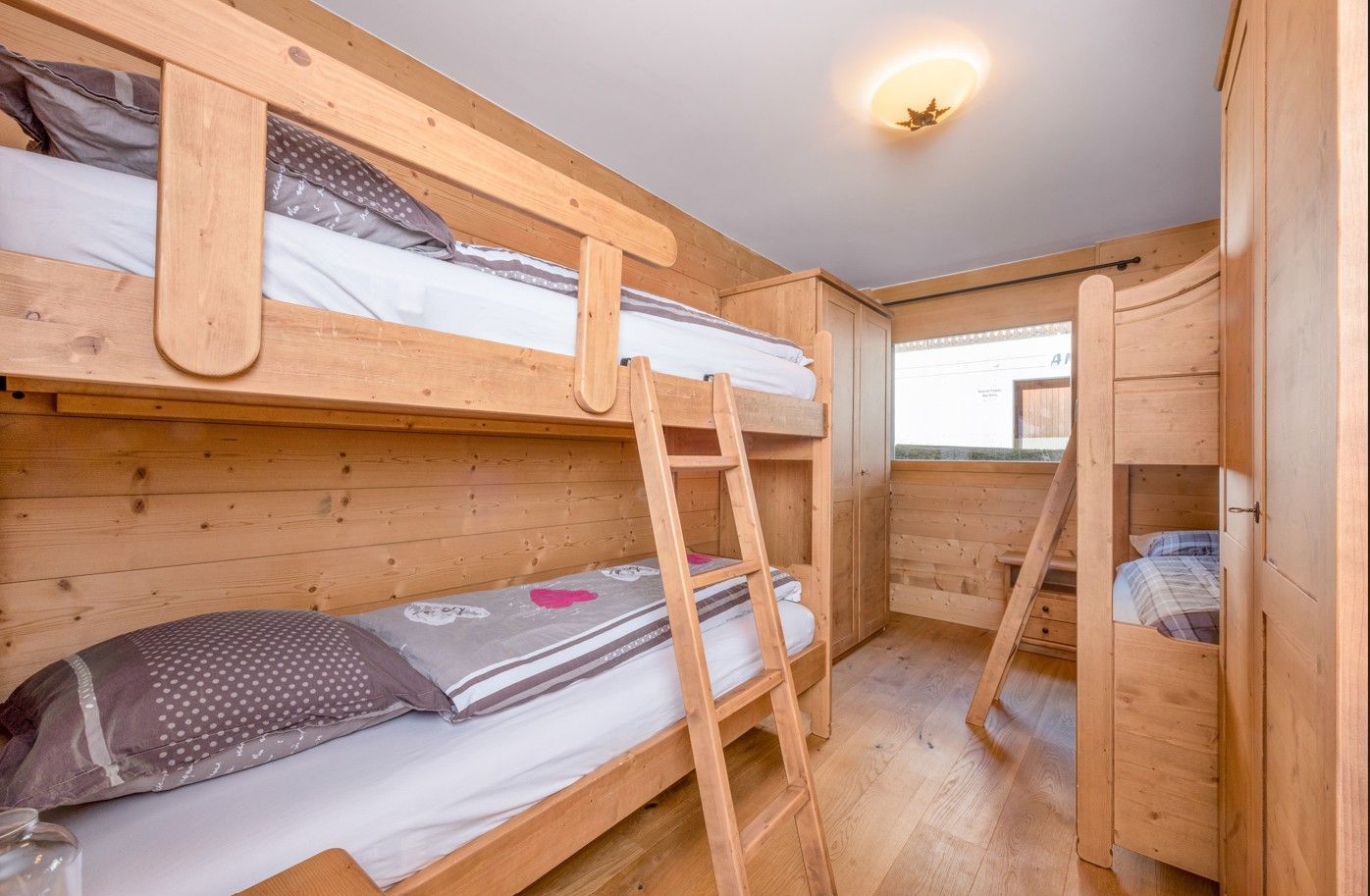 Lits superposés en bois dans une chambre aux boiseries ; deux lits sont visibles.