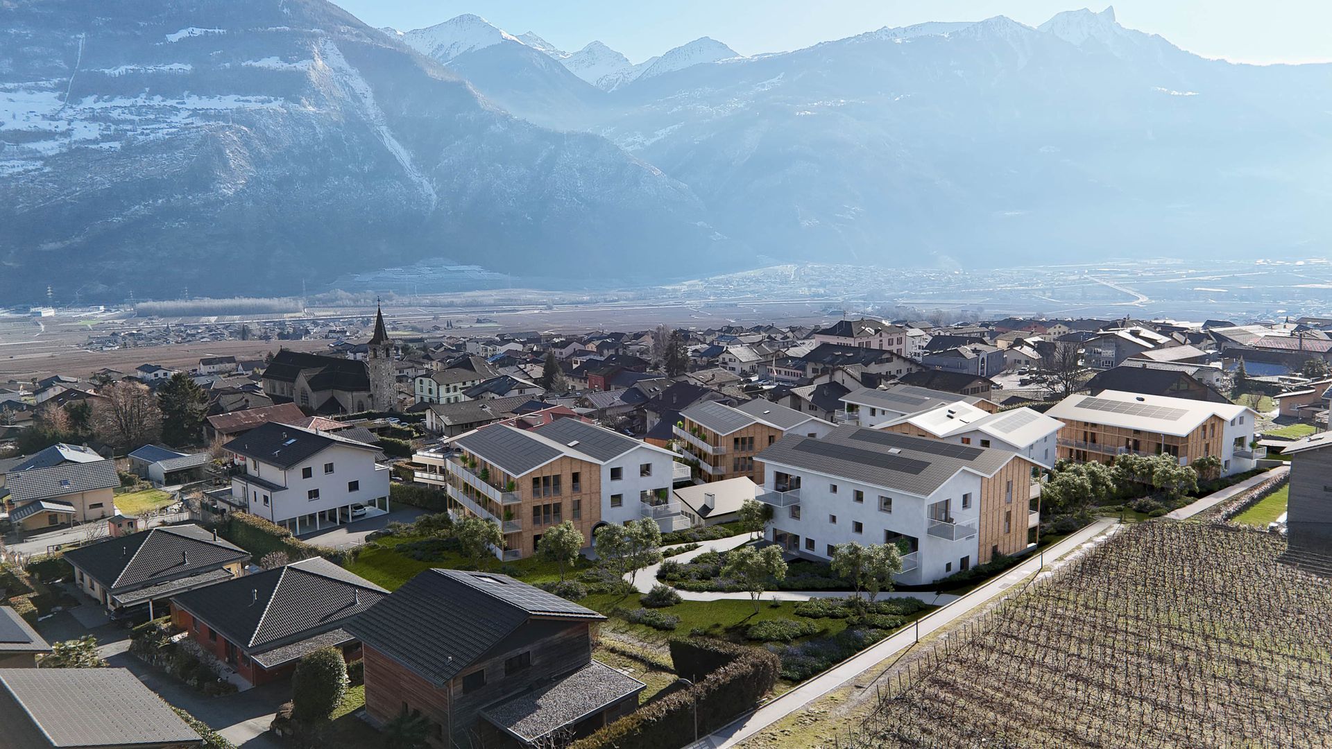 Vue aérienne d'une ville avec des bâtiments modernes et des montagnes enneigées en arrière-plan.