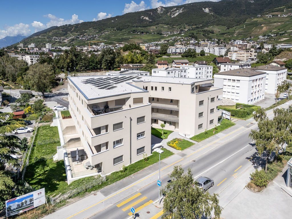 Immeubles d'appartements modernes avec panneaux solaires, vue sur la ville et les montagnes.
