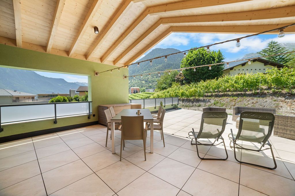 Terrasse extérieure avec sièges donnant sur les montagnes et les vignobles.