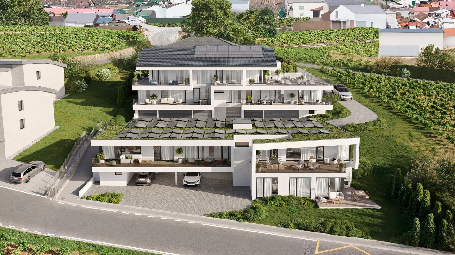 Immeuble d'appartements moderne avec balcons et panneaux solaires, situé à flanc de colline au milieu des vignes.