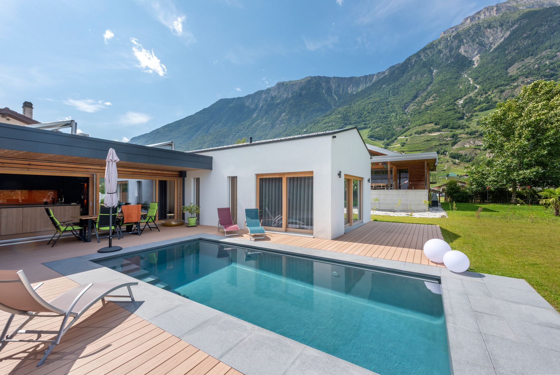 Piscine et maison moderne avec vue sur les montagnes par une journée ensoleillée.