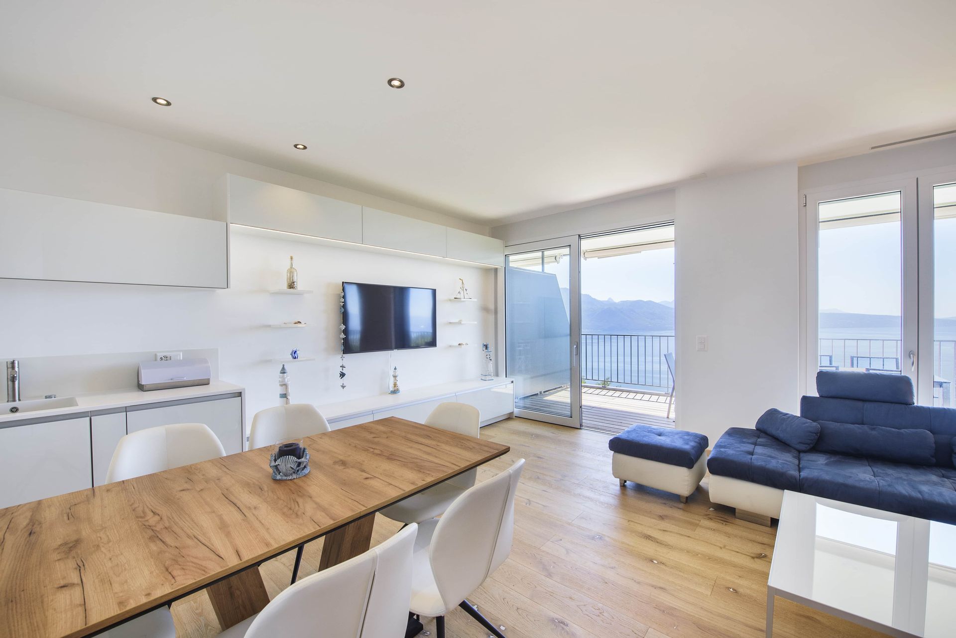 Salon moderne avec cuisine, coin repas et balcon donnant sur l'eau.