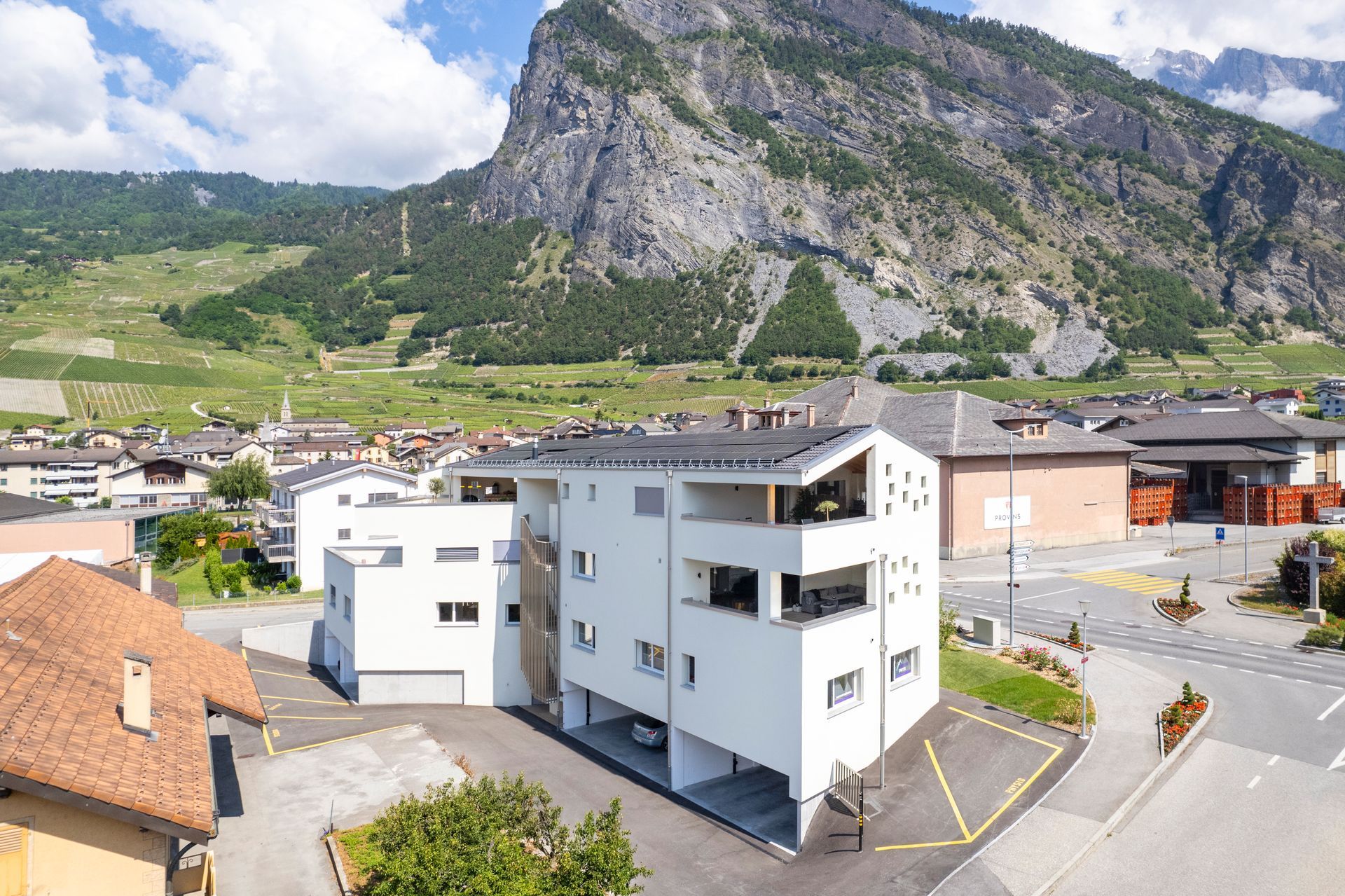 Immeuble d'appartements blanc moderne dans une ville au pied d'une grande montagne.