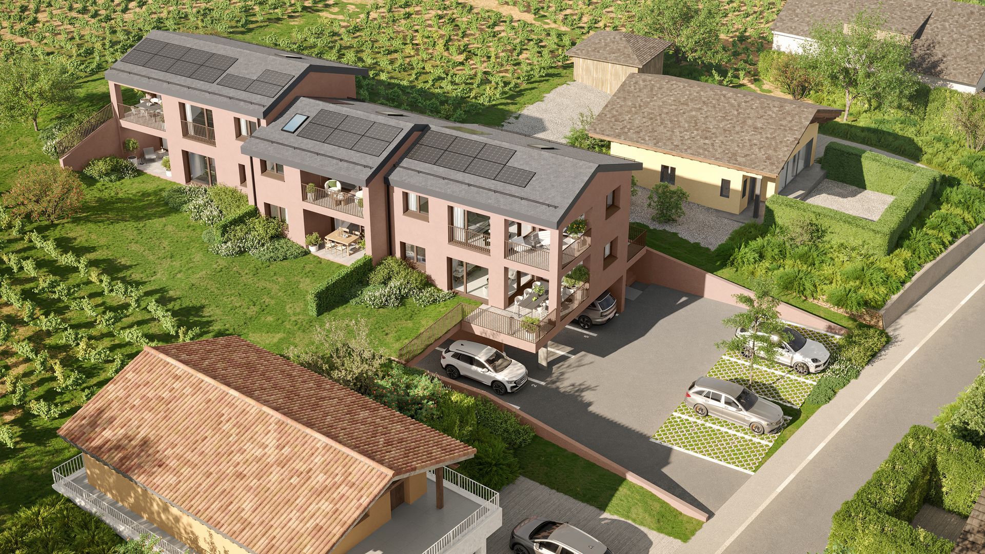 Immeubles résidentiels avec panneaux solaires, balcons et parking, entourés de pelouses verdoyantes et d'un vignoble.