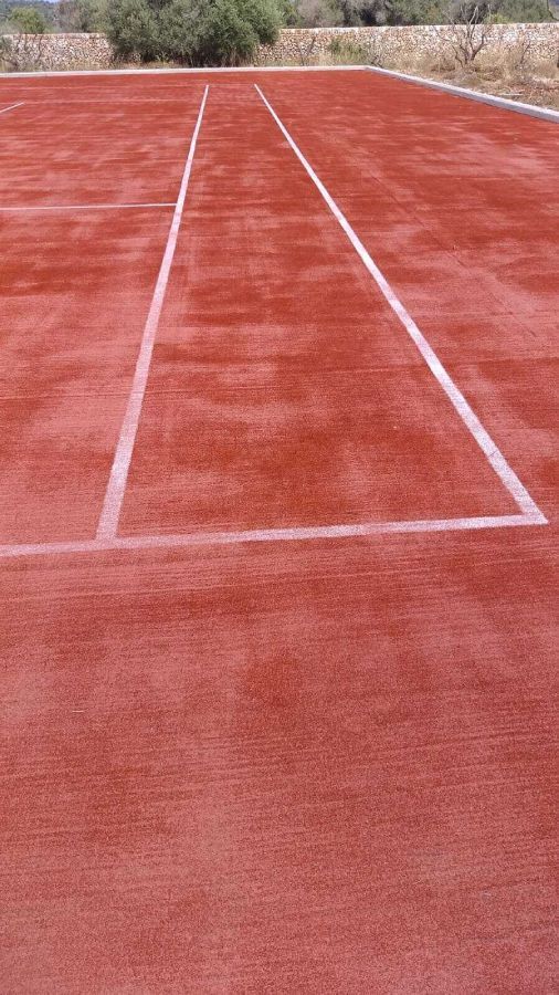 Una cancha de tenis roja con una línea blanca.
