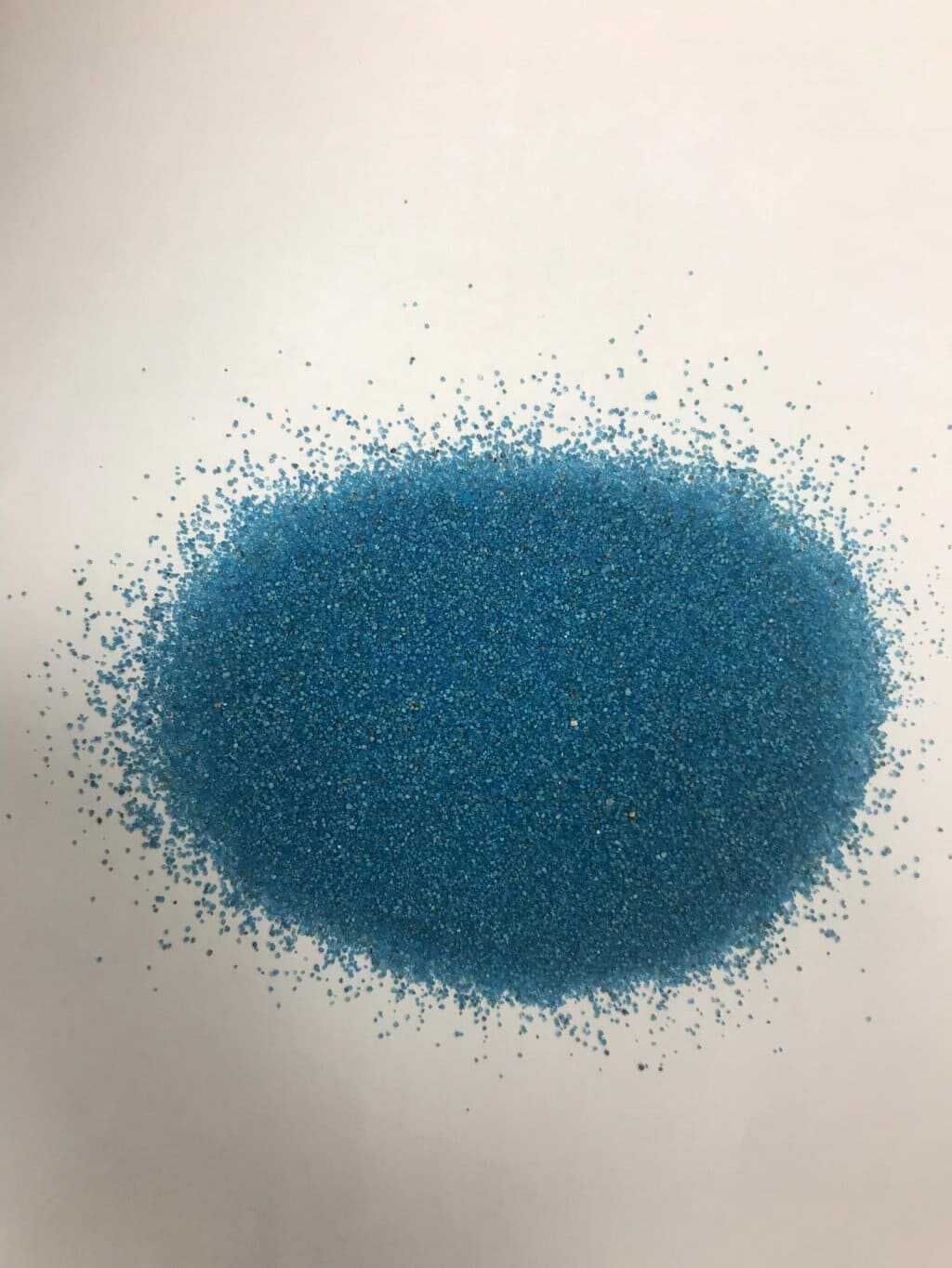 Un montón de arena azul reposa sobre una superficie blanca.