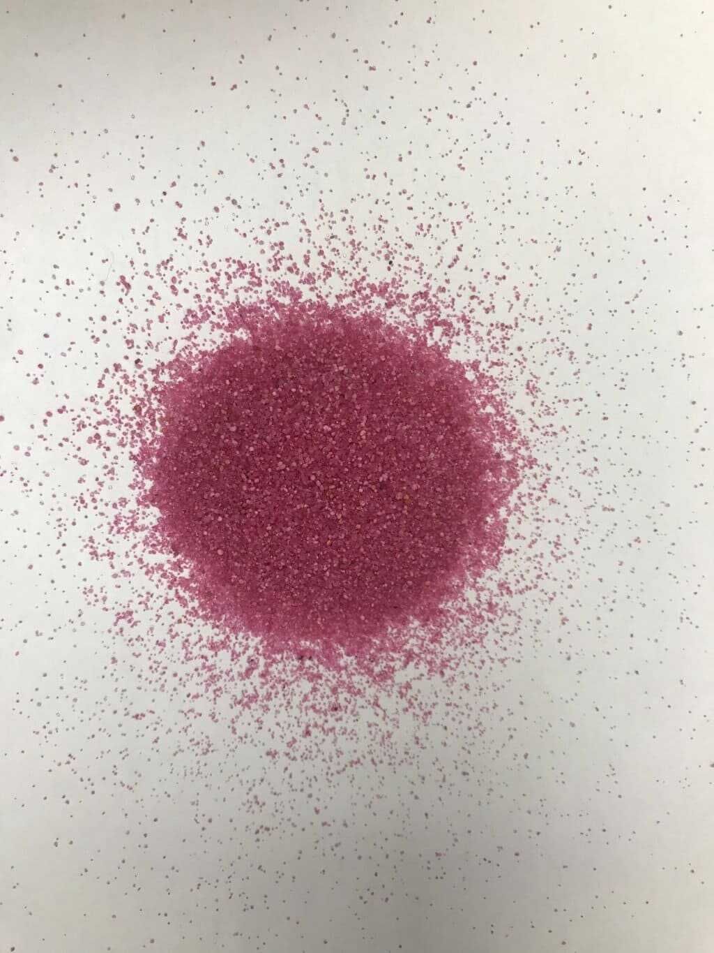 Una pila de brillantina rosa reposa sobre una superficie blanca.