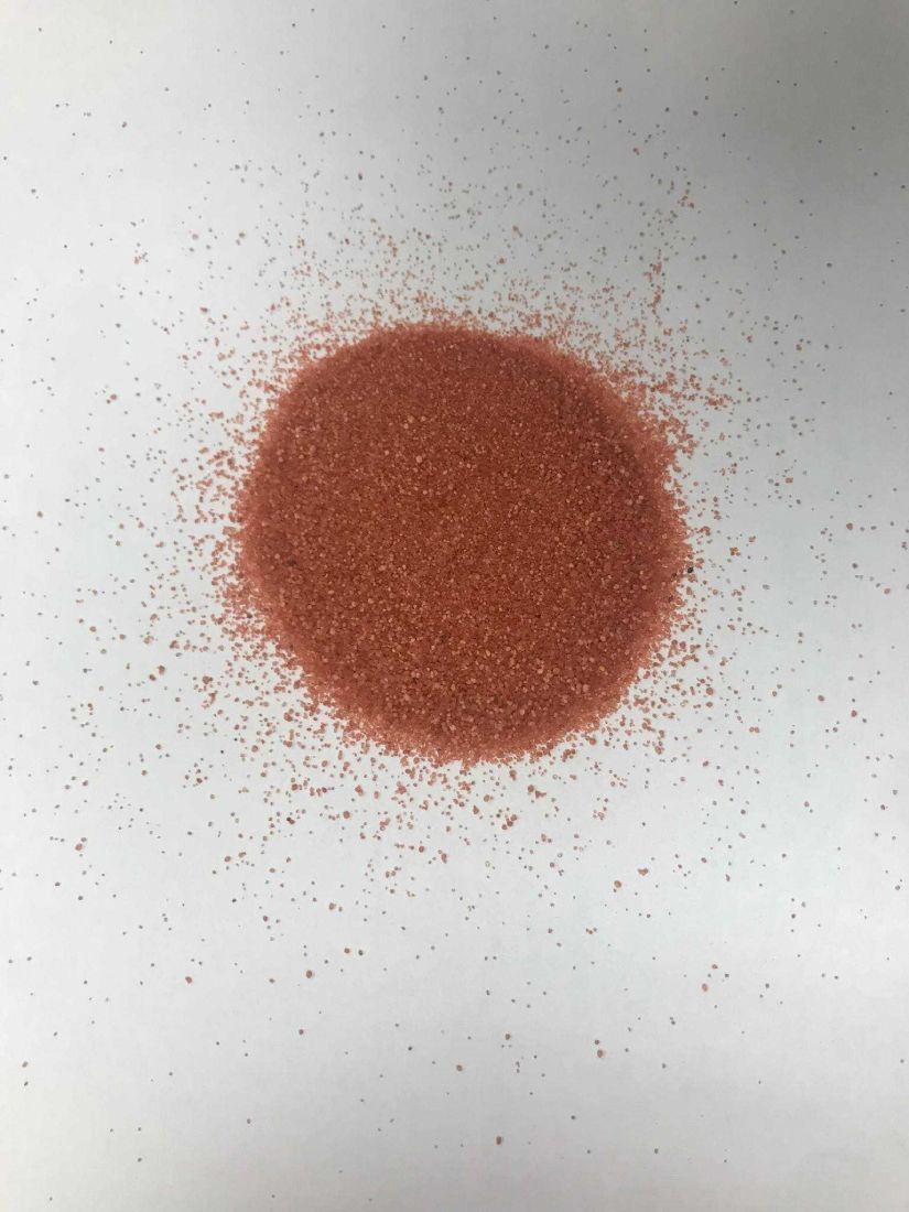 Un montón de arena roja reposa sobre una superficie blanca.