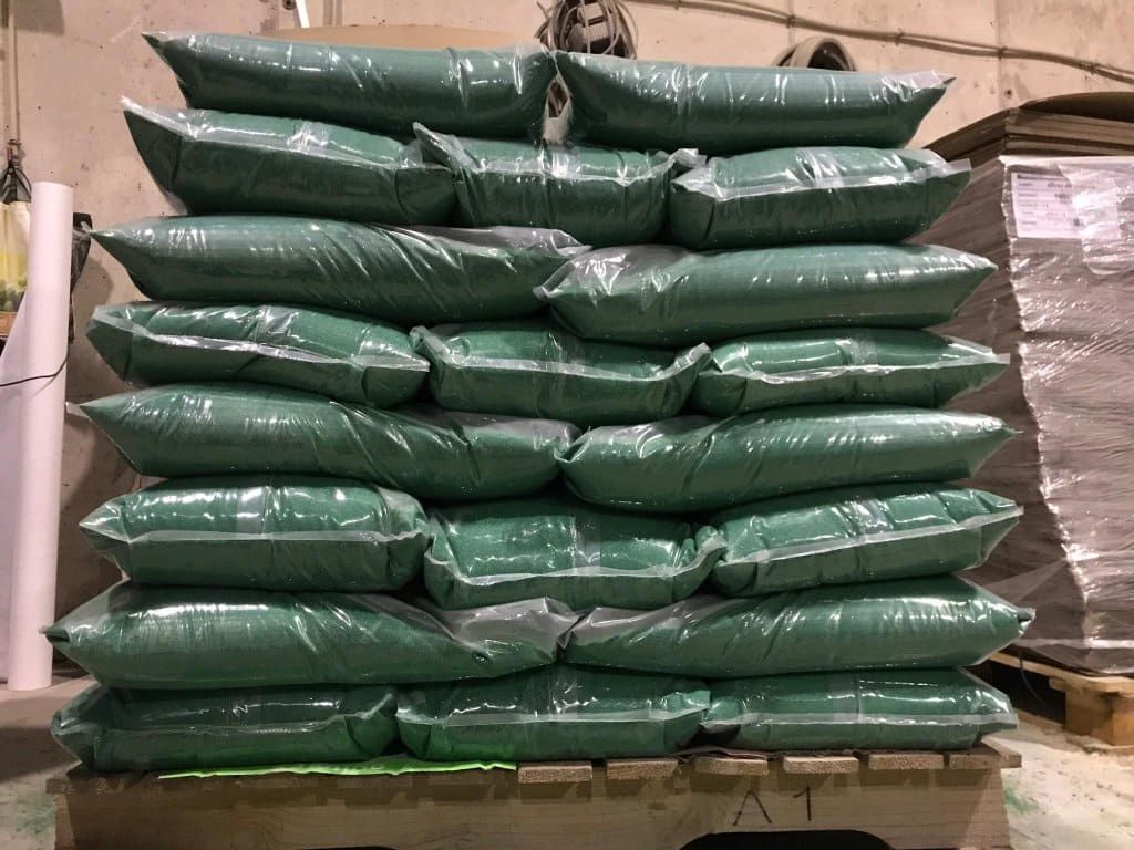 Una pila de bolsas verdes apiladas una encima de otra sobre una paleta de madera.