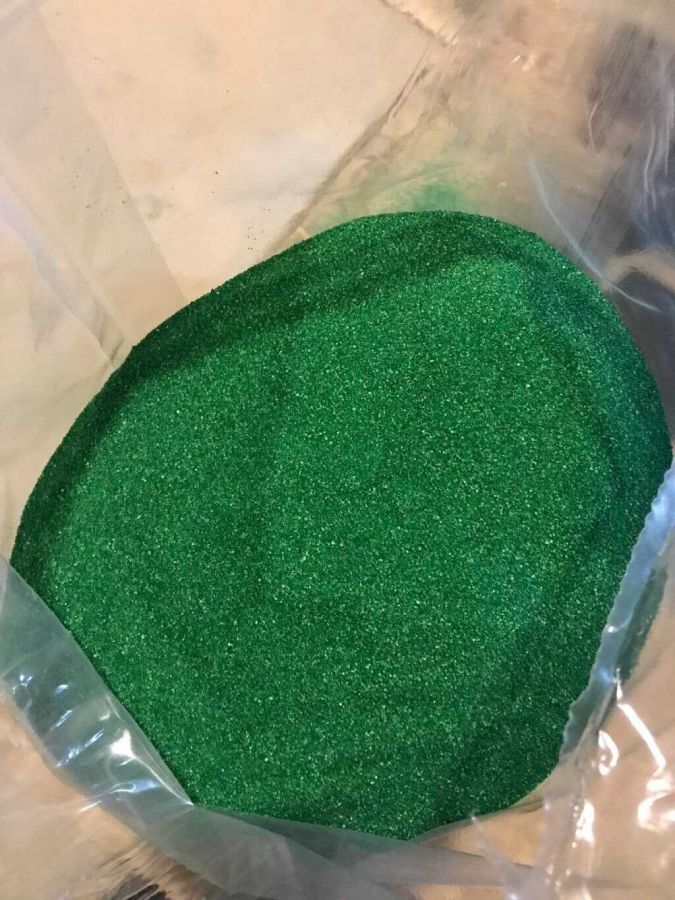 Una bolsa de brillantina verde está sobre una mesa.