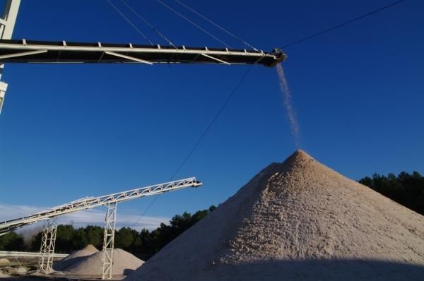 Una cinta transportadora vierte arena en una pila de arena.
