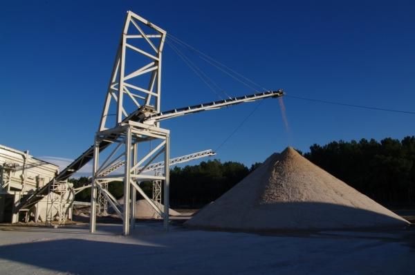 Se está cargando una gran pila de arena en una cinta transportadora.
