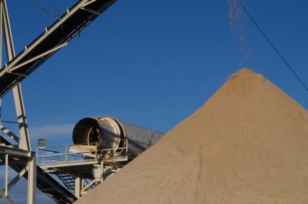 Se vierte una gran pila de arena en una cinta transportadora.
