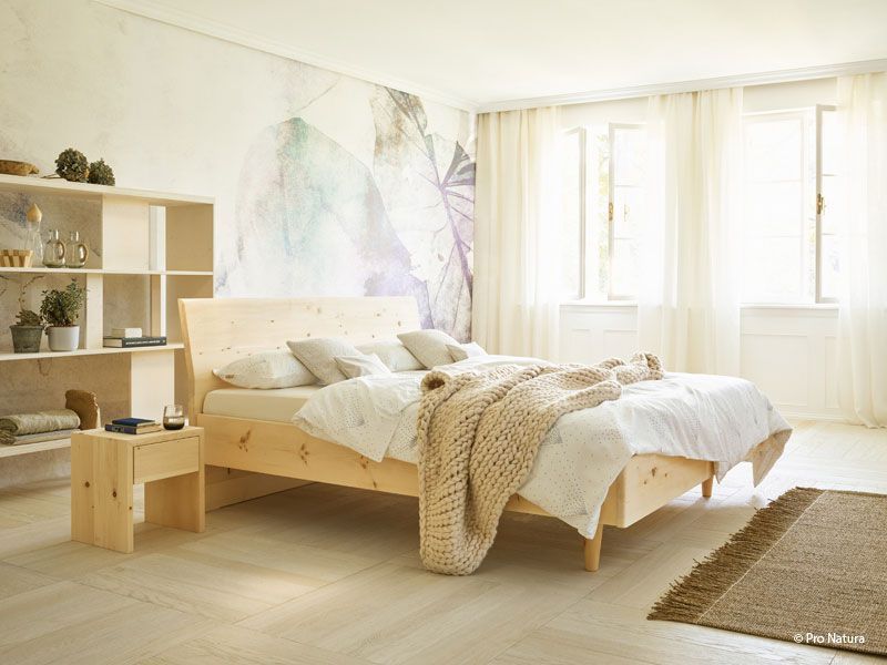 Helles, minimalistisches Schlafzimmer mit Holzbett, weißer Bettwäsche, Regalen und sonnendurchfluteten Fenstern