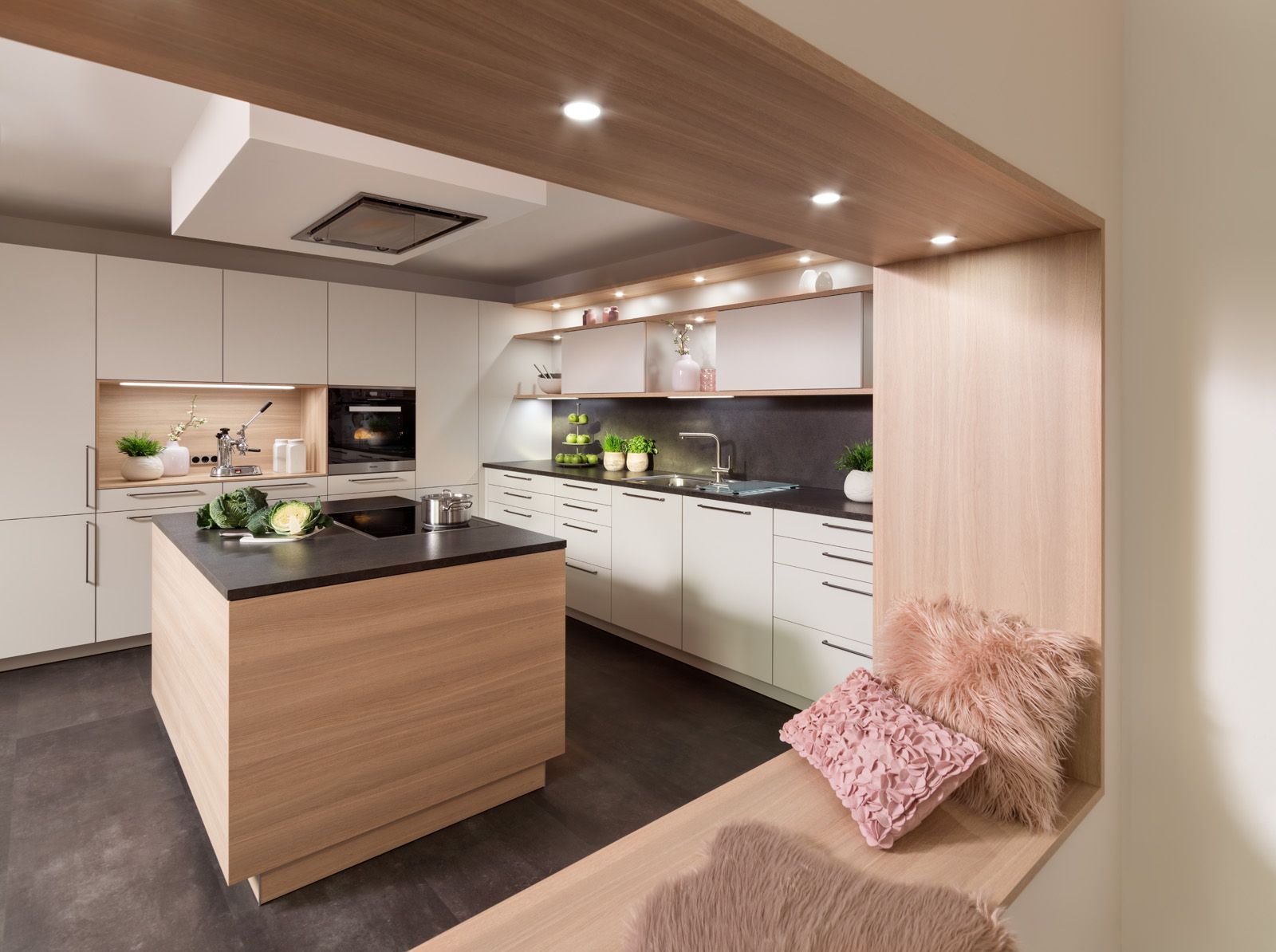 Moderne Küche mit Kochinsel, weißen Schränken, Holzelementen und einem beigefarbenen Sofa im Vordergrund