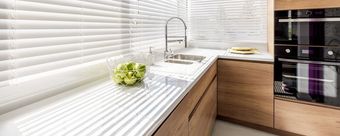 Helle, moderne Küche mit weißen Jalousien, gestreifter Arbeitsplatte, Holzschränken und Einbaubackofen