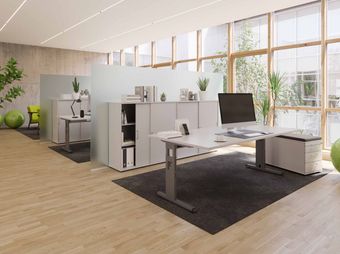 Modernes Heimbüro mit großen Fenstern, weißem Schreibtisch, Computer, Regalen und Pflanzen auf hellem Holzboden