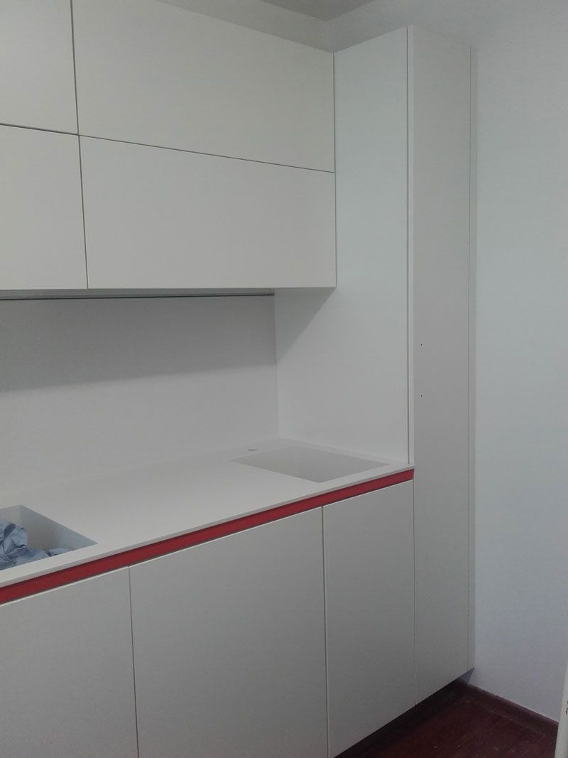 Weiße Küchenschränke und Arbeitsplatte mit rot umrandetem Rand in einer kleinen Ecke