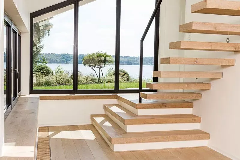 Moderne Treppe neben großen Fenstern mit Blick auf einen See und Bäume