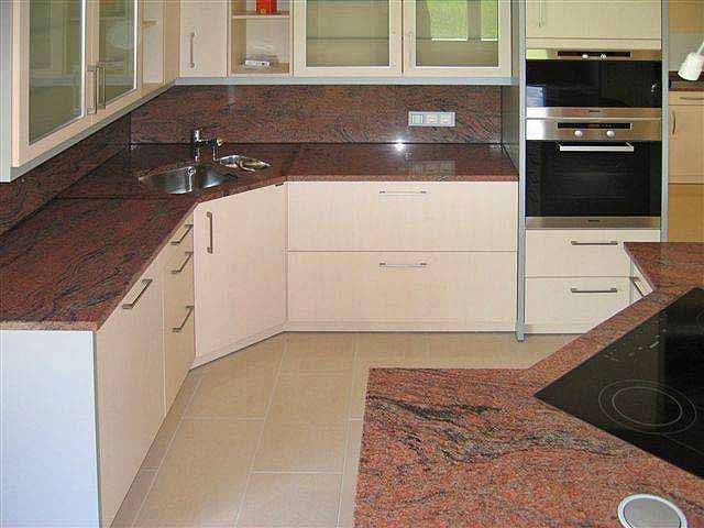 Eine Küche mit Granitoberflächen und weißen Schränken