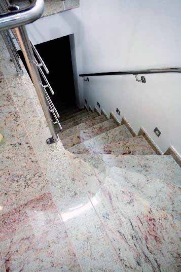 Eine Nahaufnahme einer Treppe aus Naturstein mit einem Edelstahlgeländer.