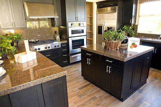 Eine Küche mit schwarzen Schränken, Arbeitsplatten aus Granit und Geräten aus Edelstahl.