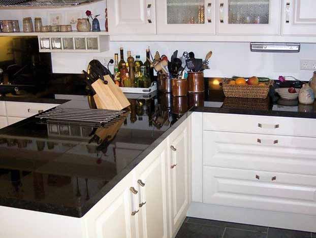 Eine Küche mit schwarzen Naturstein Arbeitsplatten und weißen Schränken