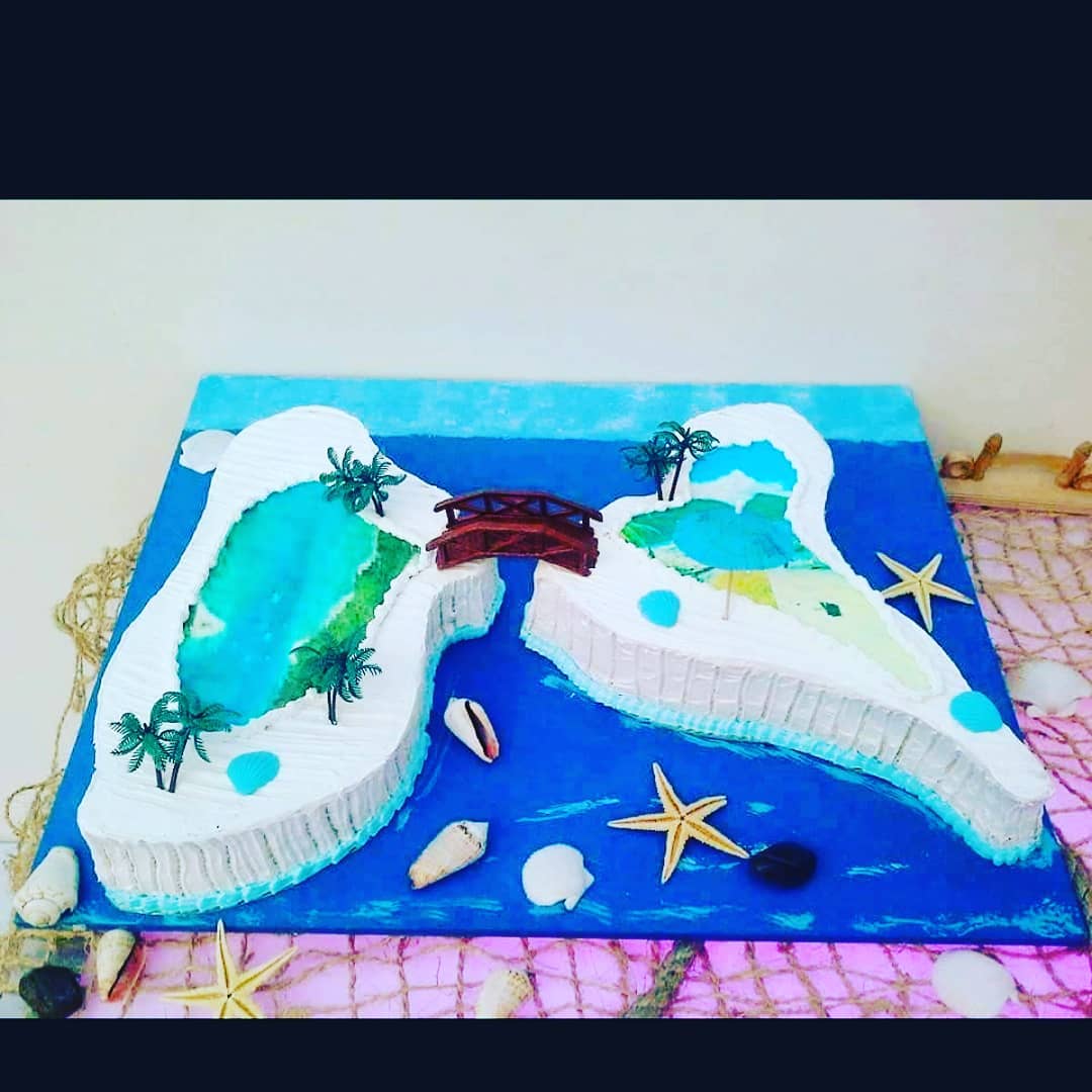 Gâteau d'île avec océan bleu, pont, palmiers, coquillages et étoiles de mer.