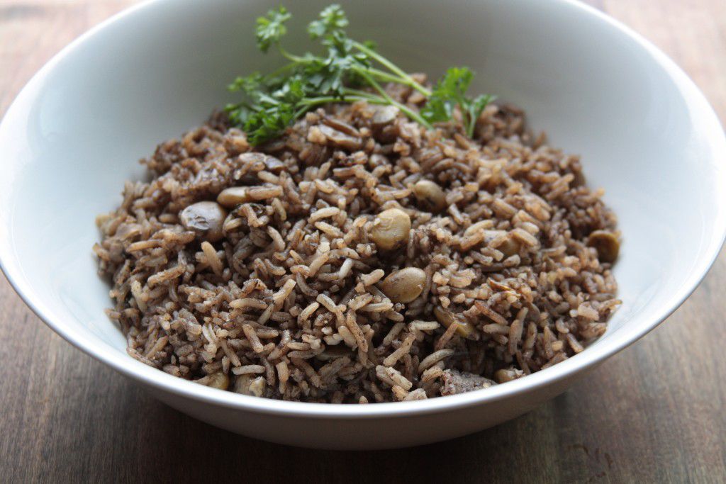 Bol de riz brun et de lentilles, garni de persil, sur une table en bois.