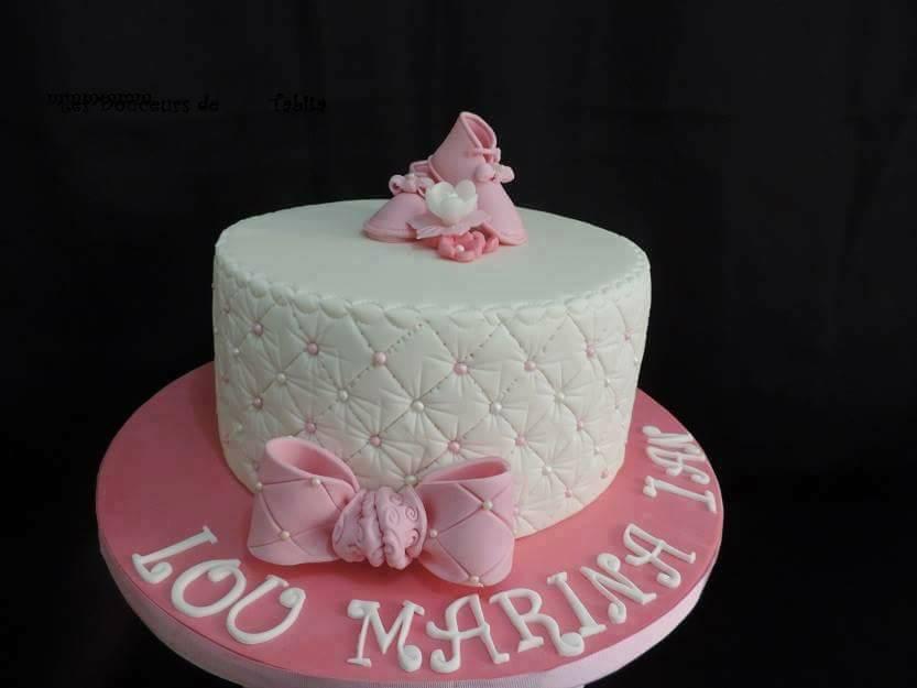 Gâteau matelassé rose et blanc avec nœud, décoration de chaussure de bébé et nom « Lou Marina 1st » sur la base.