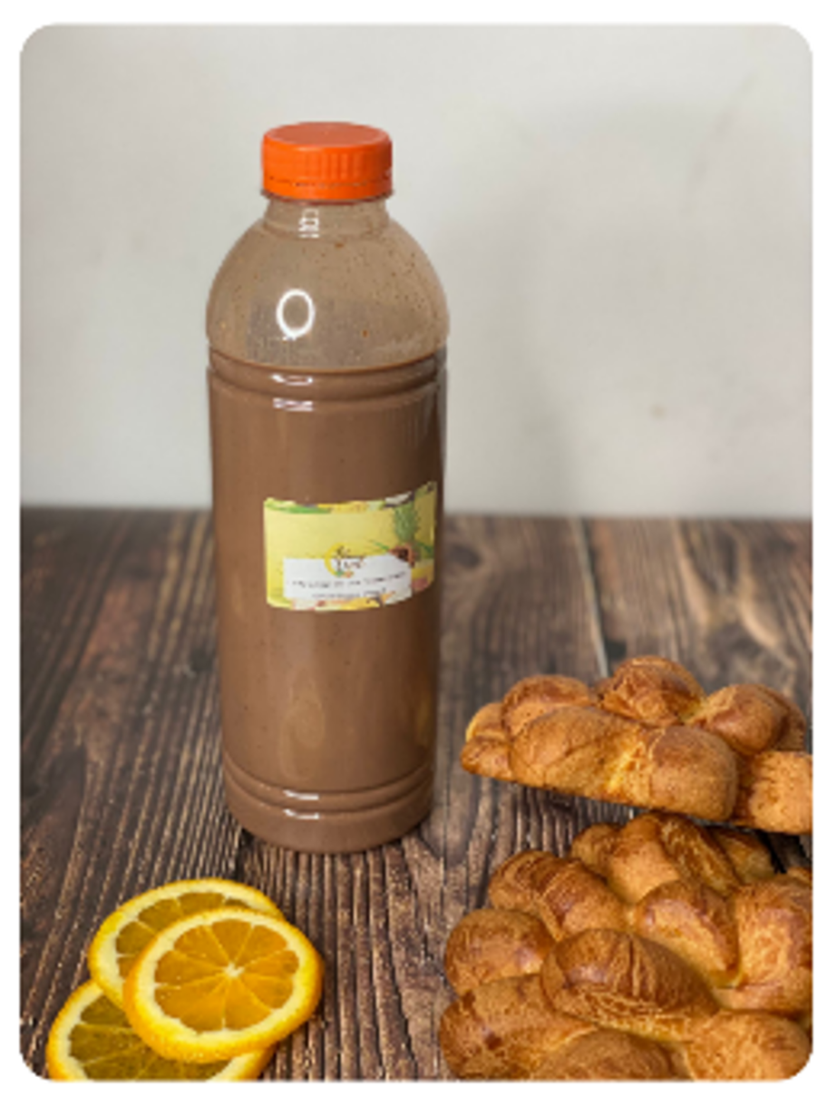Boisson au chocolat en bouteille avec des tranches d'orange et du pain sur une table en bois.