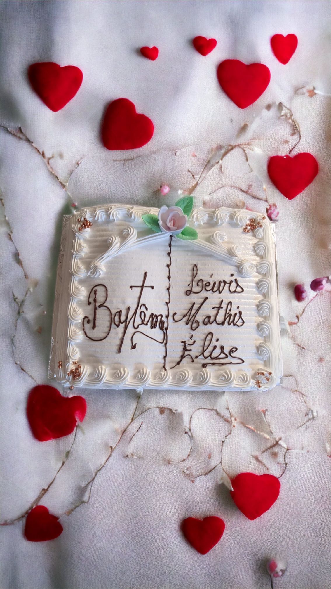 Gâteau de baptême avec les prénoms Lewis, Mathis et Élise. Cœurs rouges dispersés.