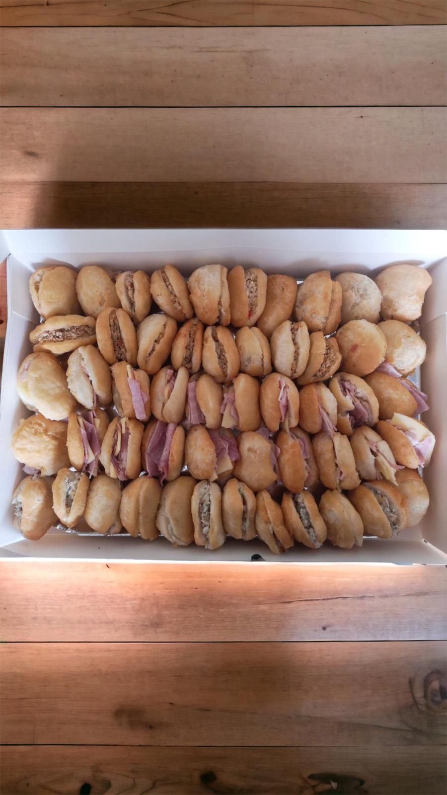 Plateau de macarons assortis sur une table en bois. La plupart sont de couleur beige, fourrés de crème et de violet.