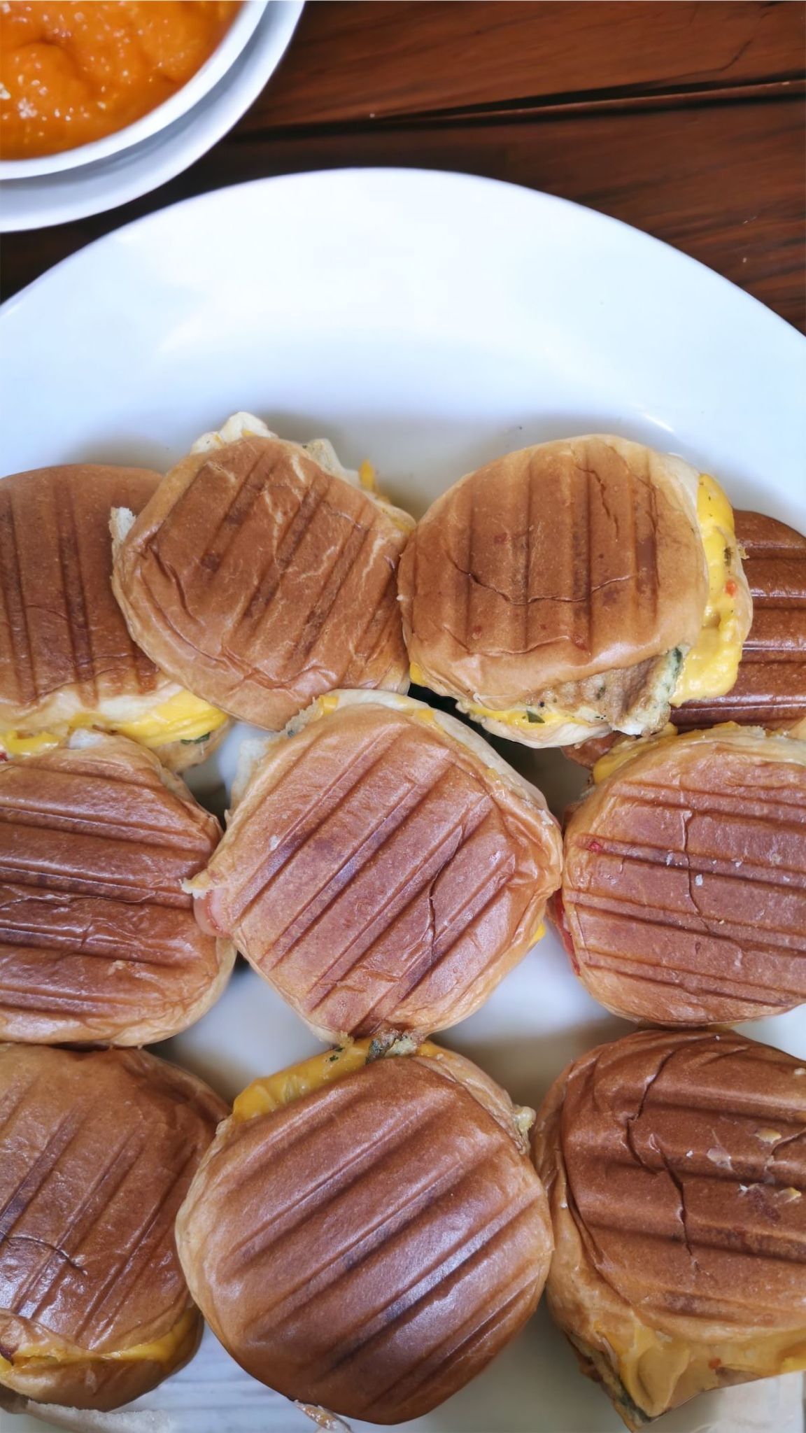 Sandwichs grillés sur une assiette blanche, servis avec un petit bol de sauce à l'orange.