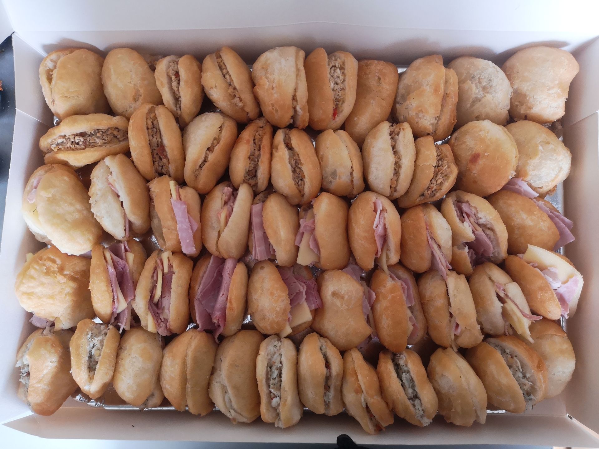 Boîte de mini sandwichs avec garnitures variées, prêtes à manger.