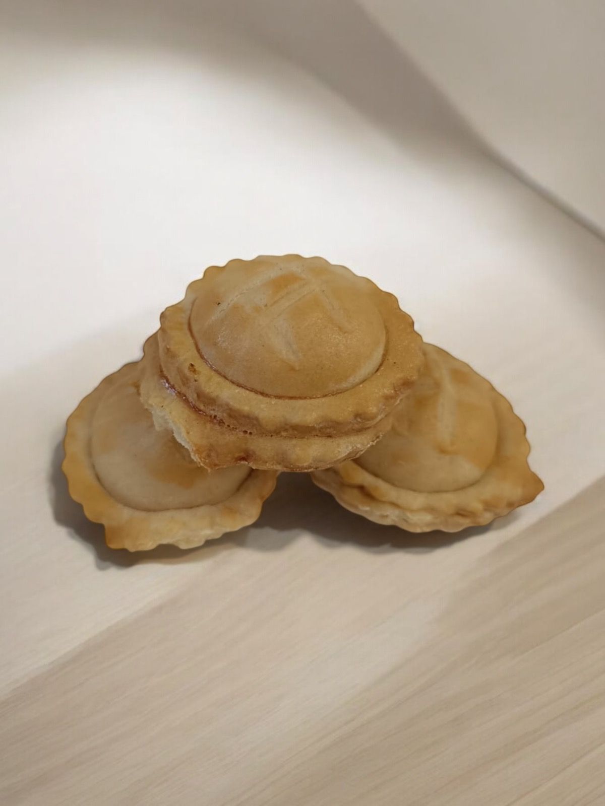 Trois pâtisseries cuites au four empilées sur une surface en bois clair.