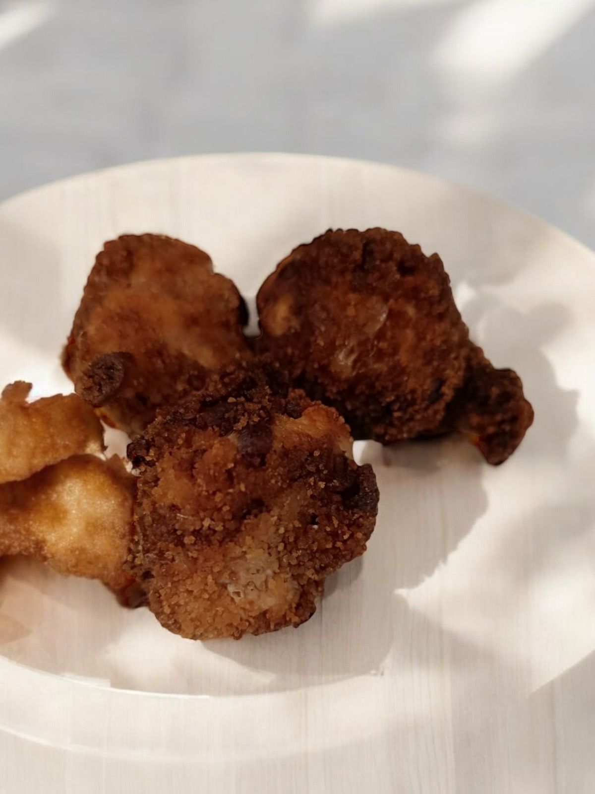 Morceaux de poulet frits sur une assiette blanche. Enrobage doré et croustillant.