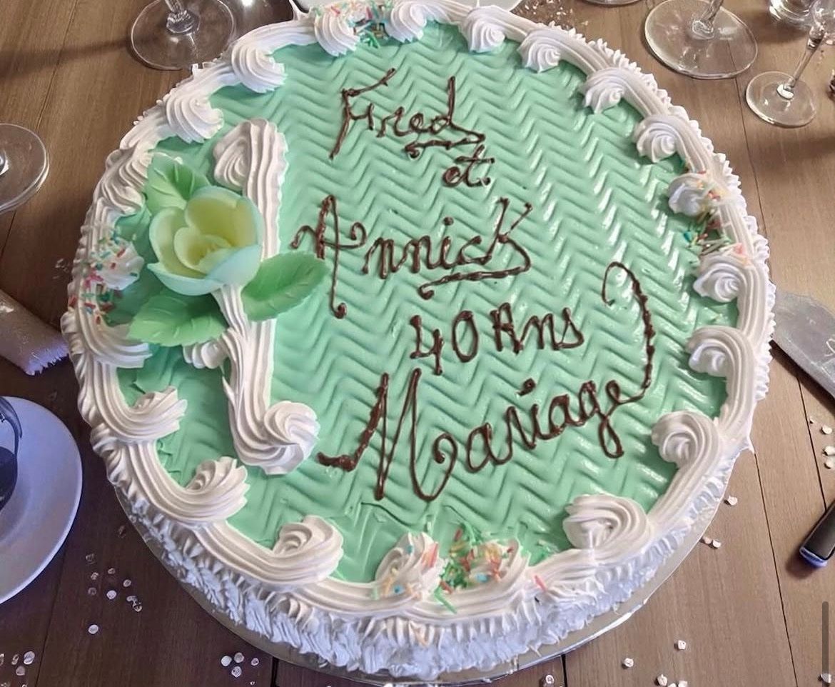 Un gâteau d'anniversaire vert menthe avec un glaçage blanc et des inscriptions en chocolat posé sur une table