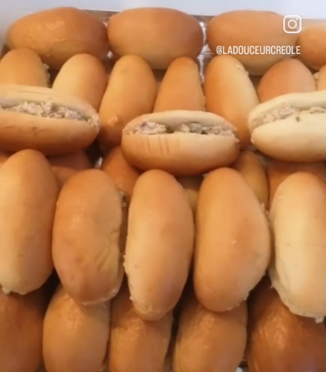 Gros plan sur de nombreux petits pains fourrés. Certains sont coupés en deux et garnis d'une garniture crémeuse.