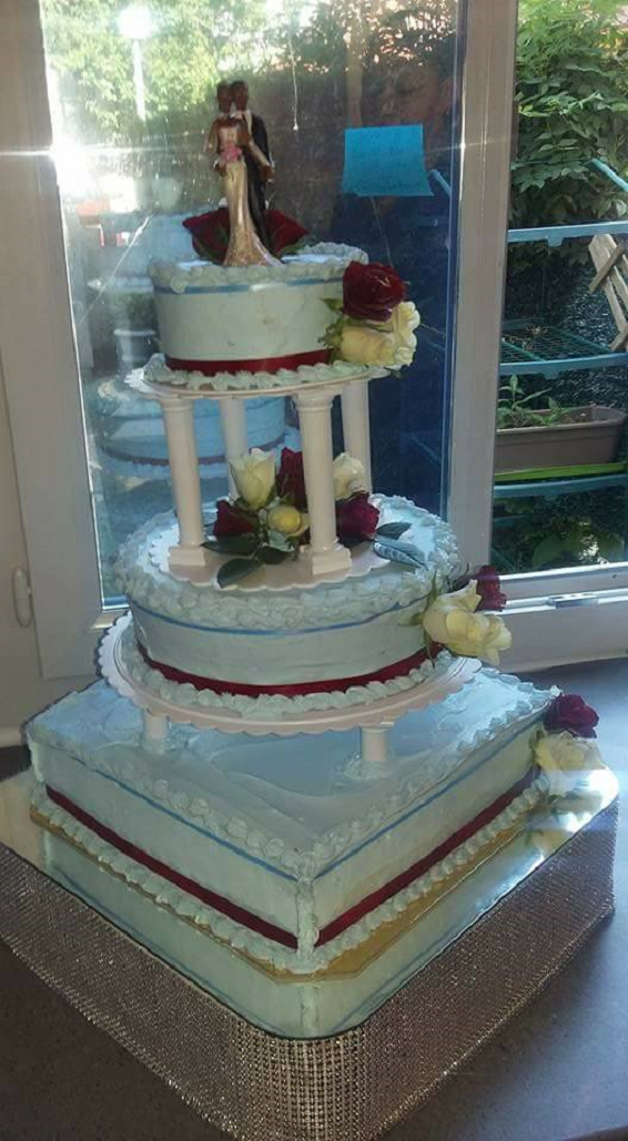 Gâteau de mariage bleu clair à trois étages avec des détails bordeaux et blancs, surmonté de figurines de mariés.