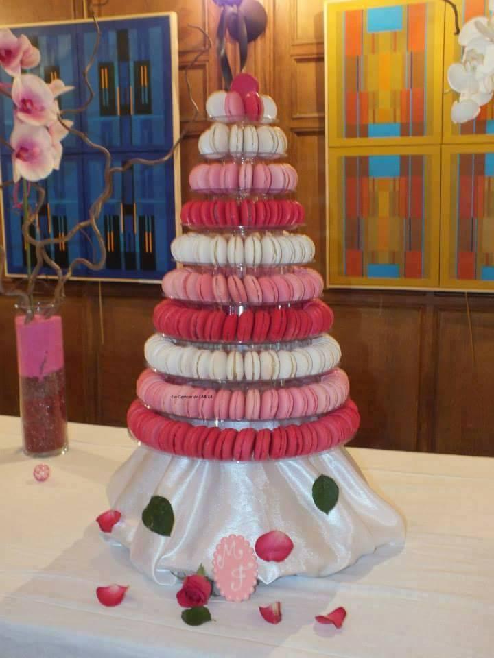 Tour de macarons aux nuances de rose variées, sur une base en satin blanc, avec des décorations florales.