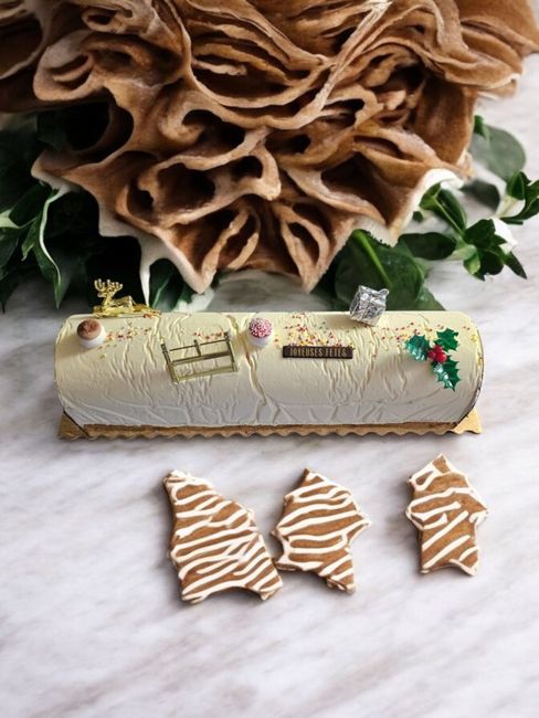 Bûche blanche décorée de biscuits et de verdure sur un support marbré.