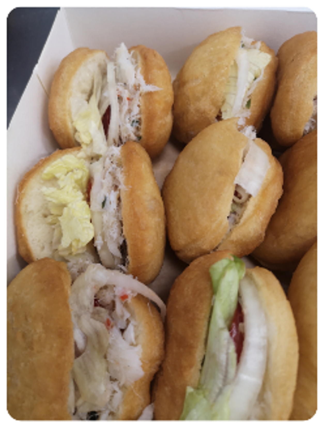 Boîte de sandwichs à la pâte frite garnis de crabe, de laitue et de tomates.