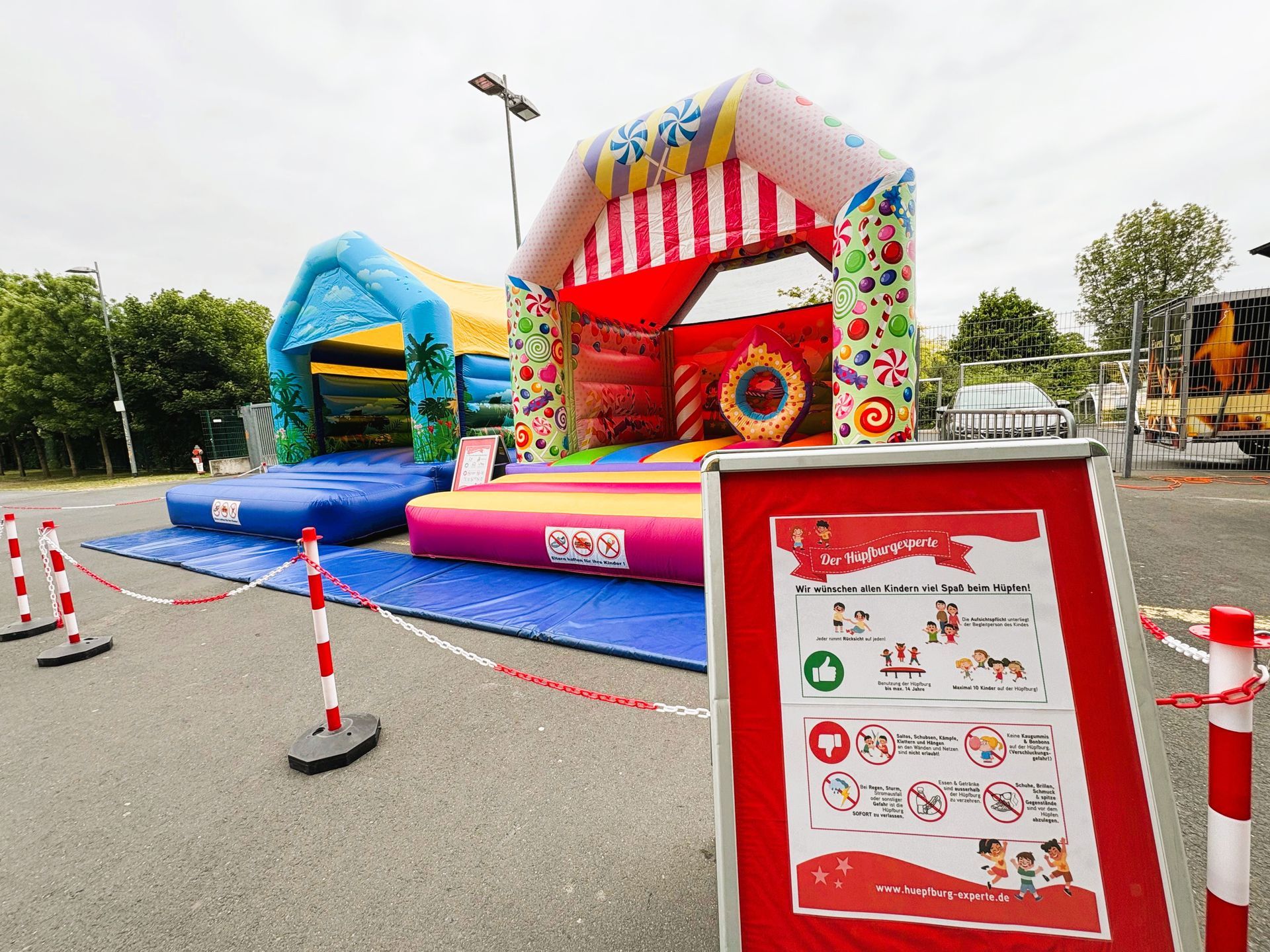 Open-Air-Festival mit Bühne, Hüpfburgen, Essensständen und einer Menschenmenge auf einem Stadtplatz.