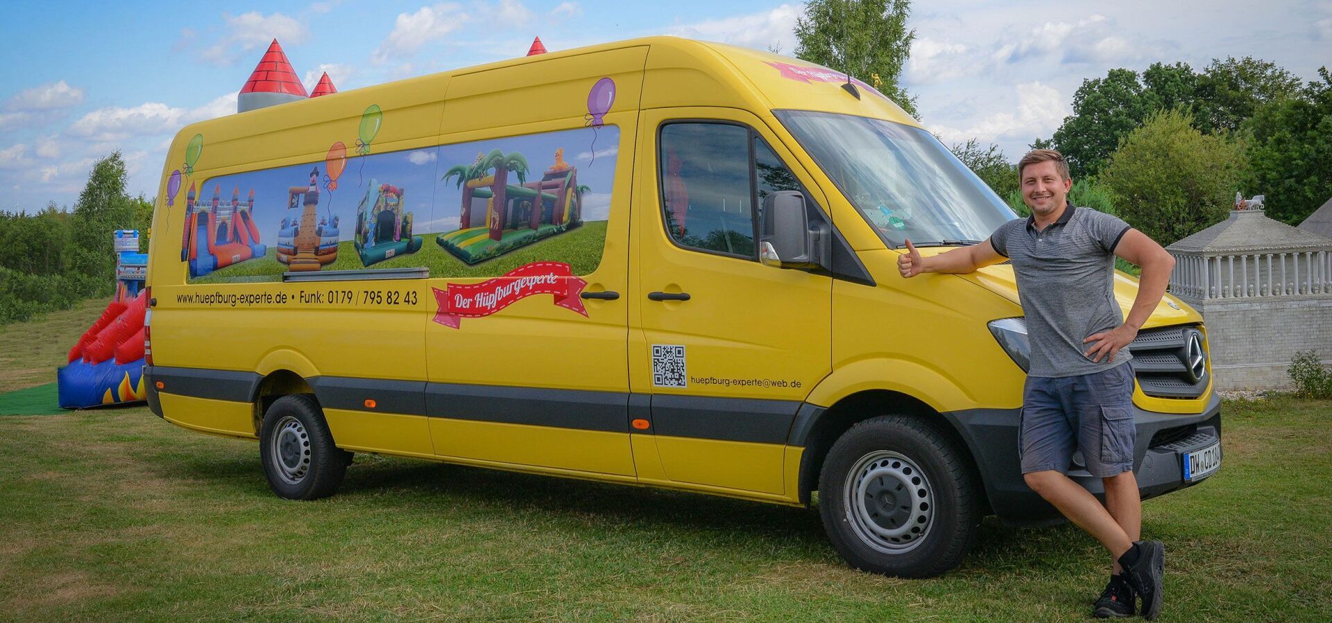 Ein Mann steht neben einem gelben Lieferwagen auf einem Feld.